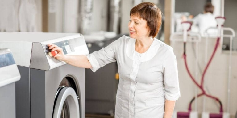 Female Staff Operating Washing Machine in Laundry Room at an Assisted Living Facility