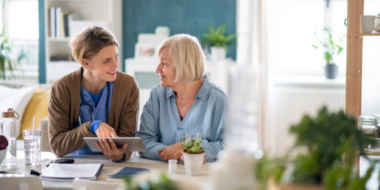 Female Nurse Reviewing Care Plan on Tablet with Senior Resident at an Assisted Living Facility