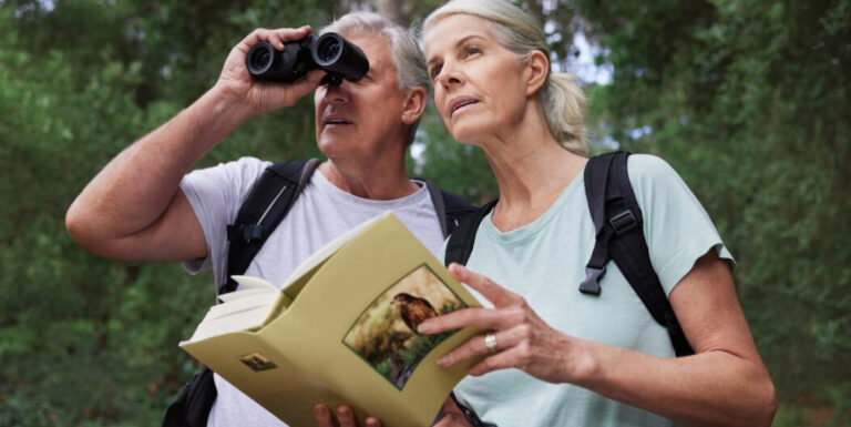 Elderly Couple Bird Watching with Binoculars and Guidebook from Assisted Living Facility
